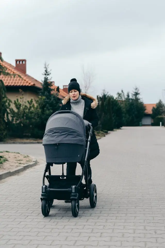 A person pushes a large, rugged-looking stroller on a residential street, suitable for jogging.