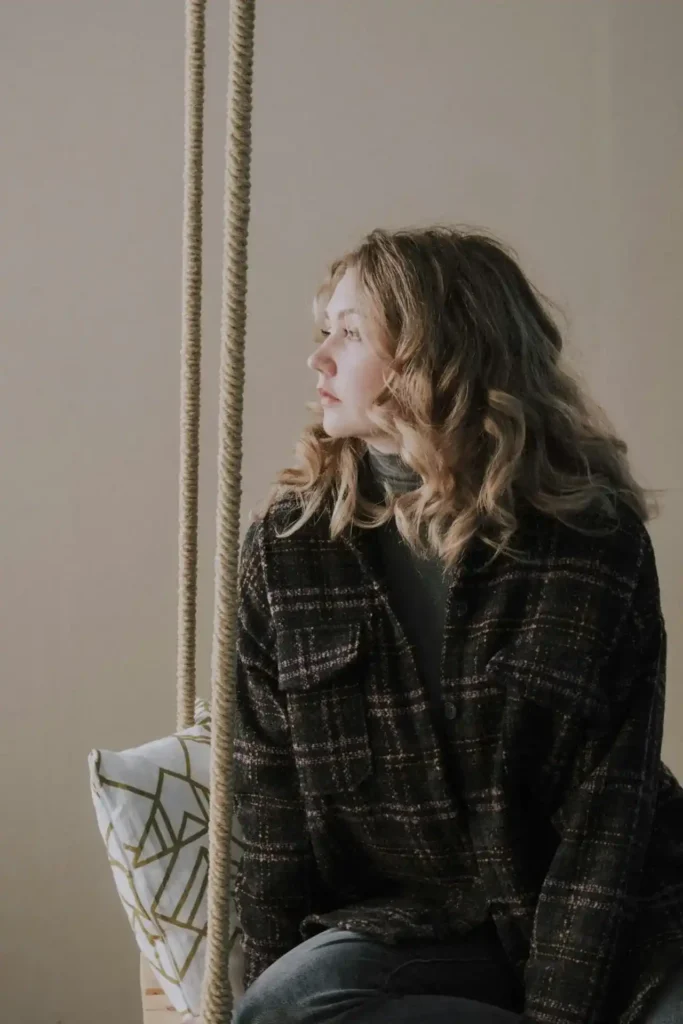 Person sitting on an indoor swing, looking thoughtfully to the side—an image illustrating the emotional ups and downs of First Trimester Mood Swings.