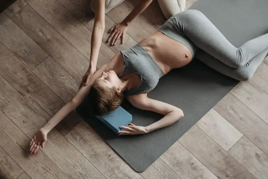 Pregnant woman doing a supported side-lying stretch on a yoga mat with props—safe Exercise for Trimester Pregnancy.