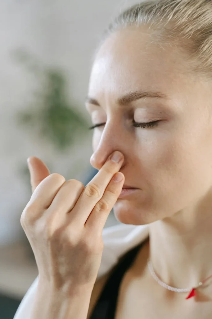 Close-up of a woman gently pinching her nostrils to stop a bleed—illustrating Second Trimester nosebleeds and congestion (pregnancy rhinitis).