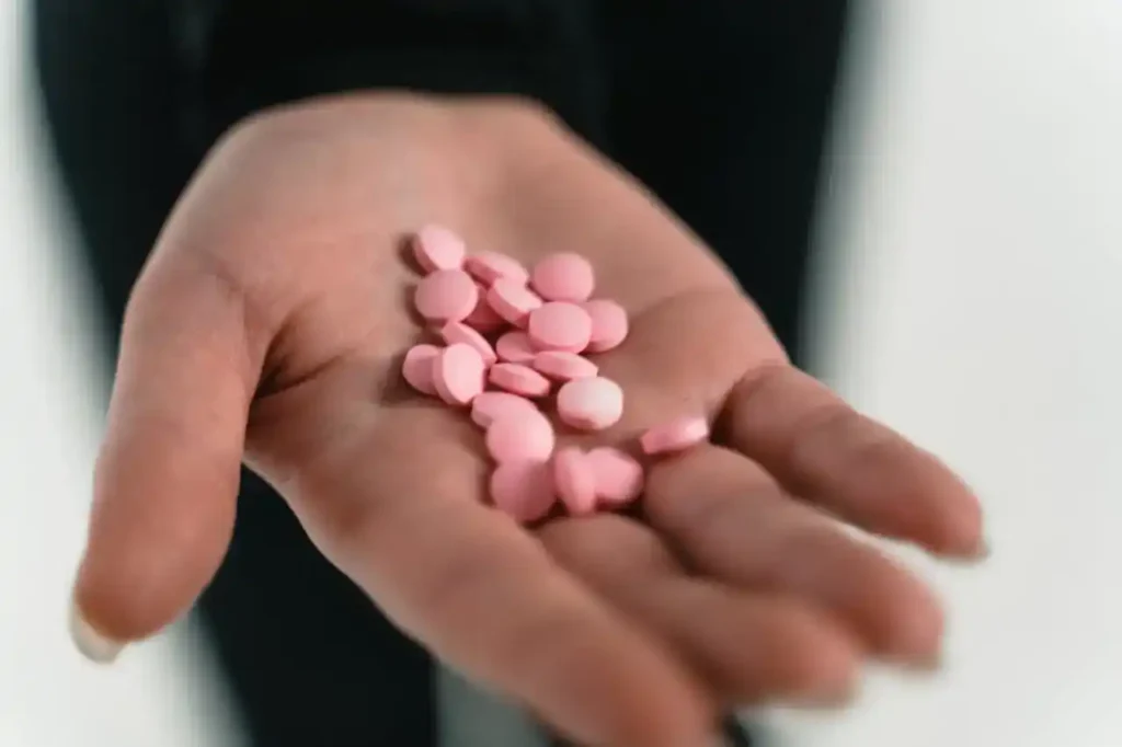 Open hand holding small pink tablets—visual of prenatal vitamins for conception.