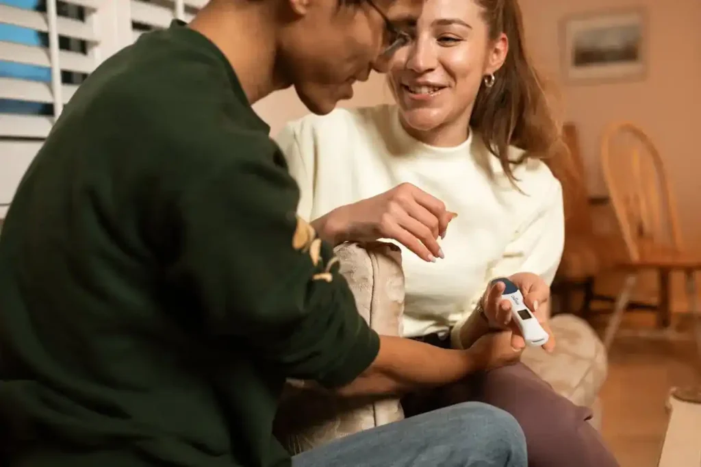Smiling couple at home looking at a digital ovulation tester together—illustrating what a fertile window means in real life.