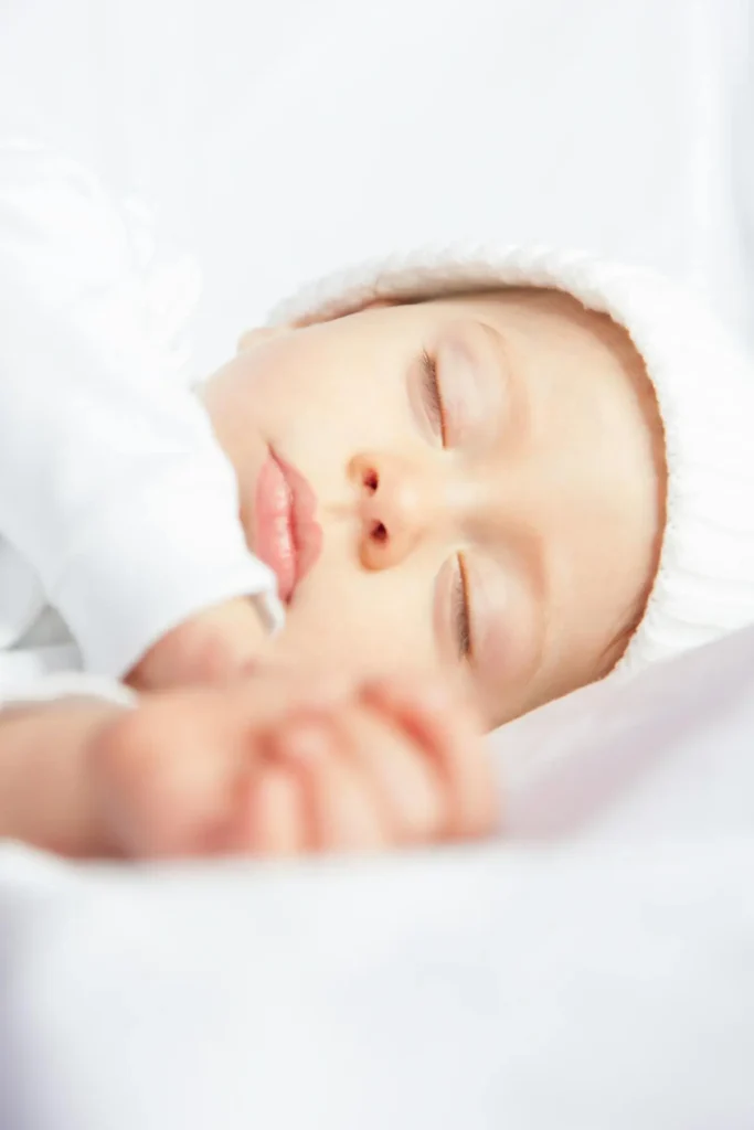 Newborn sleeping peacefully in a safe sleep space, representing a gentle newborn sleep schedule by age (0–3 months).